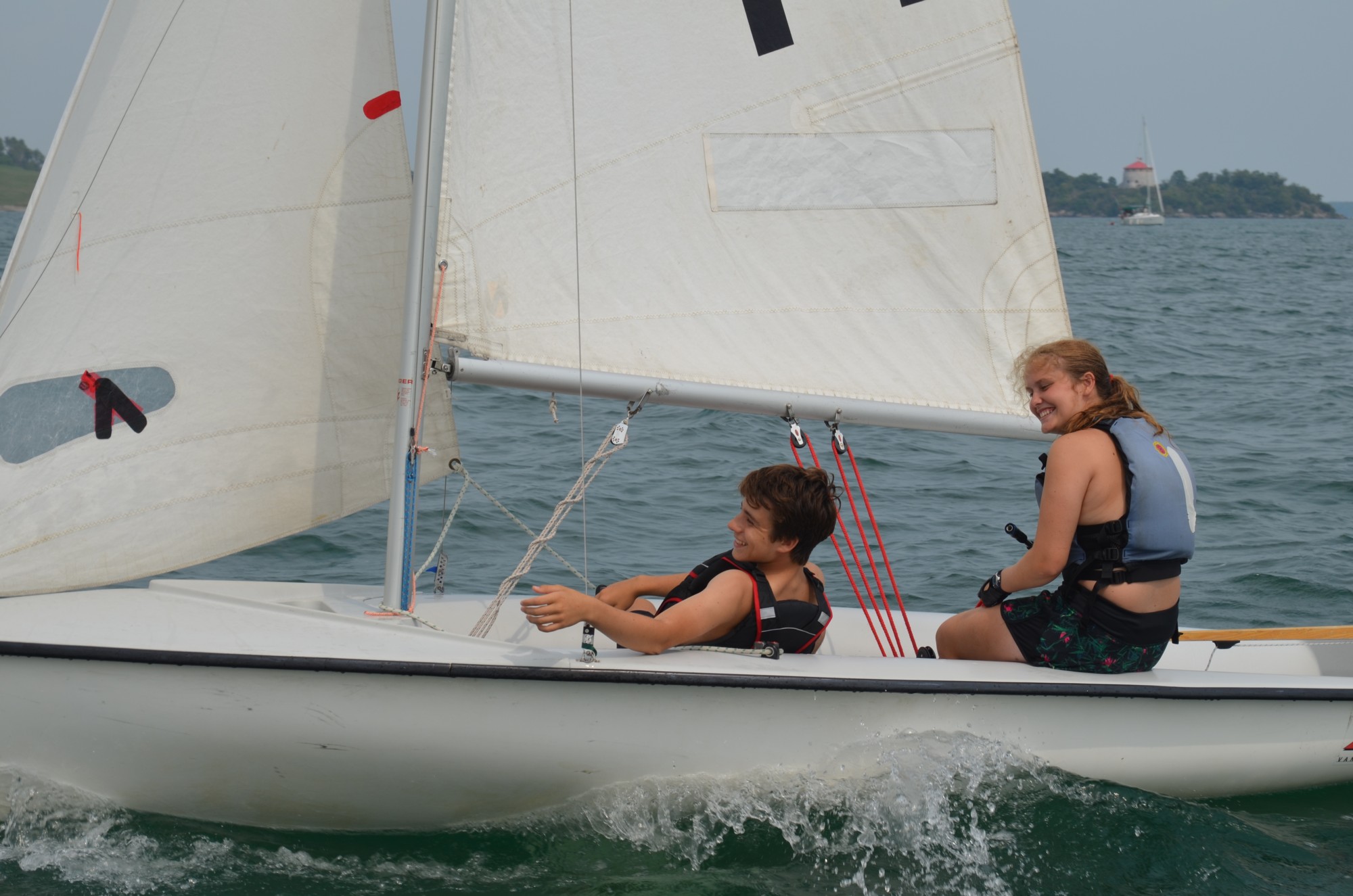 Two kids sailing a dinghy sailboat